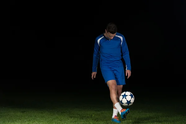 Jogador de futebol profissional chutando bola isolada no preto — Fotografia de Stock