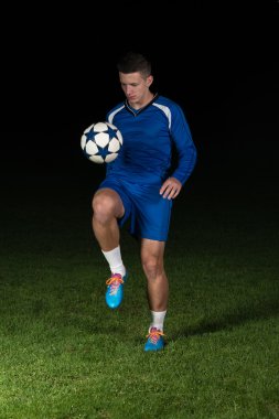 Siyah arka plan üzerine bir top ile futbol oyuncusu