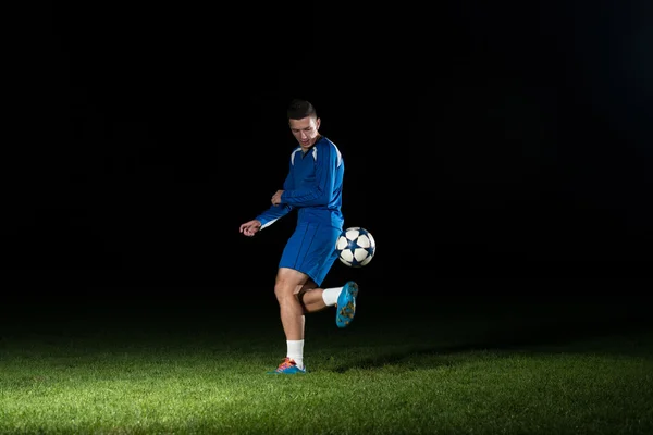 Jogador de futebol profissional chutando bola isolada no preto — Fotografia de Stock