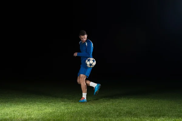 Voetbalspeler met een bal op zwarte achtergrond — Stockfoto