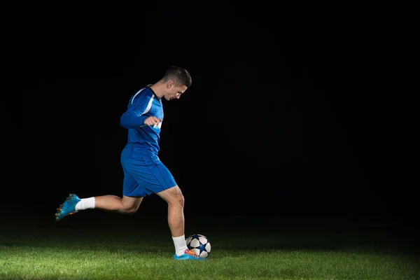 Jogador de futebol profissional chutando bola isolada no preto — Fotografia de Stock