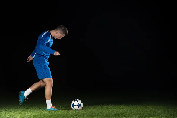 Jugador de fútbol con una pelota sobre fondo negro — Foto de Stock