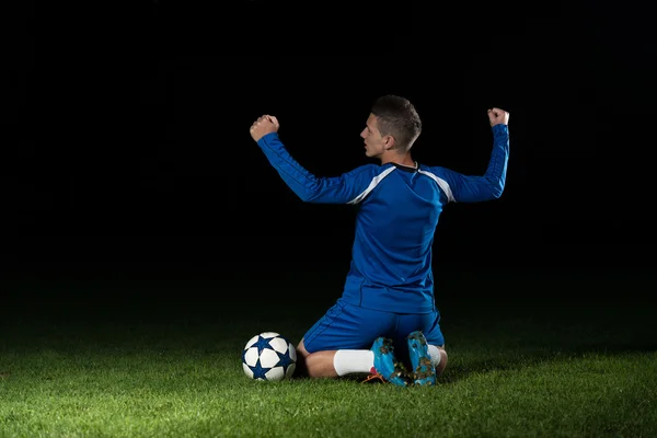 Voetbalspeler viert de overwinning op zwarte achtergrond — Stockfoto