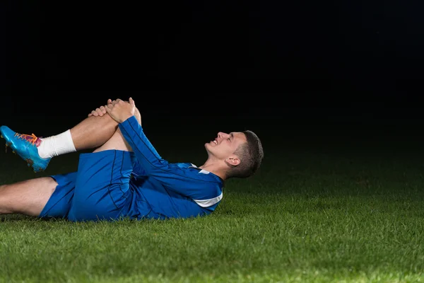 Skadade fotbollsspelare liggande på marken — Stockfoto
