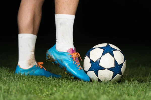 Ноги игрока с мячом на темном фоне — стоковое фото