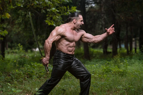 Homem muscular segurando espada antiga — Fotografia de Stock