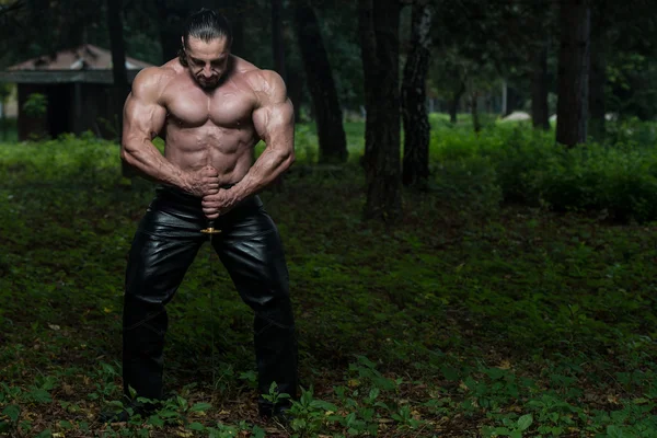 Hombre muscular sosteniendo la espada antigua — Foto de Stock