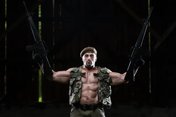 Muscular Man Holding Machine Guns — Stock Photo, Image