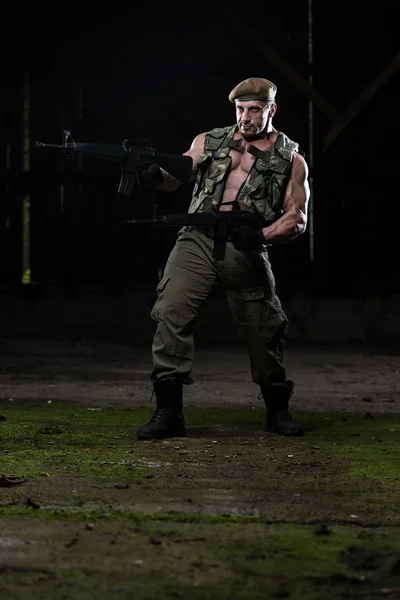 Muscular Man Holding Machine Guns — Stock Photo, Image