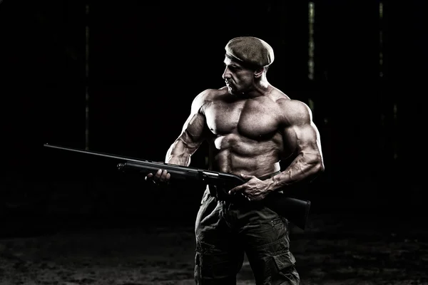 Homem muscular segurando metralhadora — Fotografia de Stock