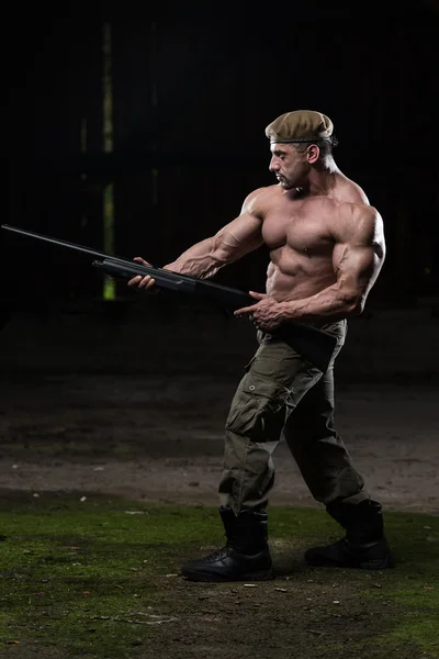 Homem muscular segurando metralhadora — Fotografia de Stock