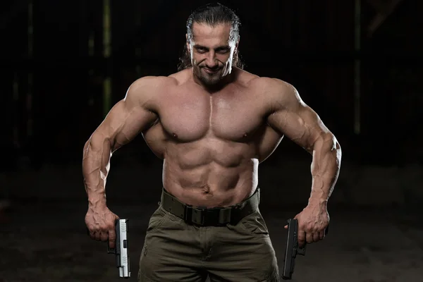 Muscular hombre sosteniendo armas — Foto de Stock