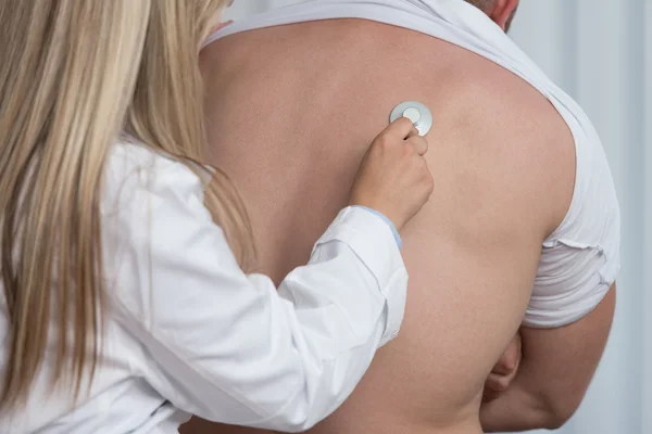 Amigável jovem pediatra médico examinando homem com estetoscópio — Fotografia de Stock