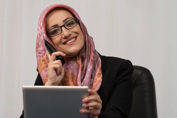 Muzułmańska kobieta rozmowa na telefon i za pomocą komputera — Zdjęcie stockowe