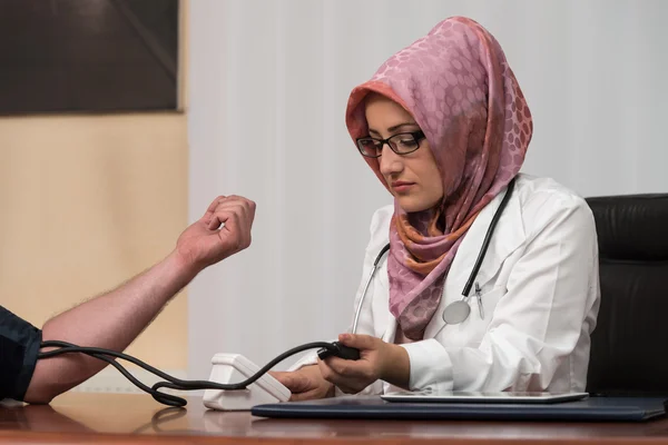 Мусульманский доктор измеряет давление крови молодого человека — стоковое фото