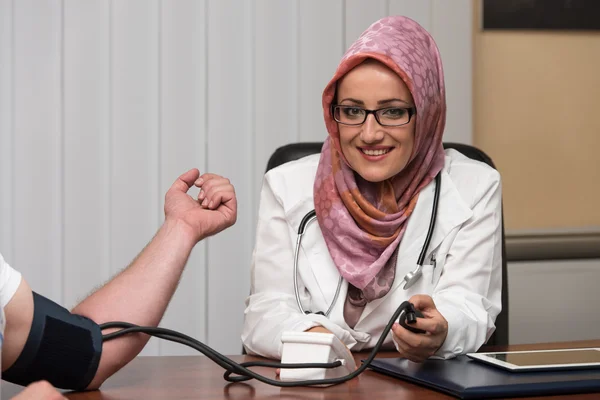 Muslimischer Arzt nimmt Blutdruck des jungen Mannes — Stockfoto