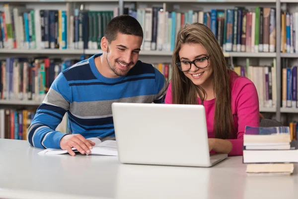 Onların Laptop bir kitaplığı kullanan genç öğrenciler — Stok fotoğraf