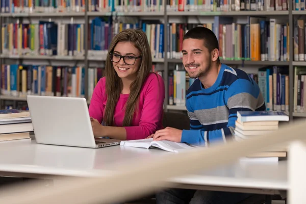 Casal de estudantes com laptop na biblioteca — Fotografia de Stock