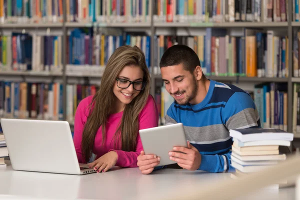 Casal de estudantes com laptop na biblioteca — Fotografia de Stock