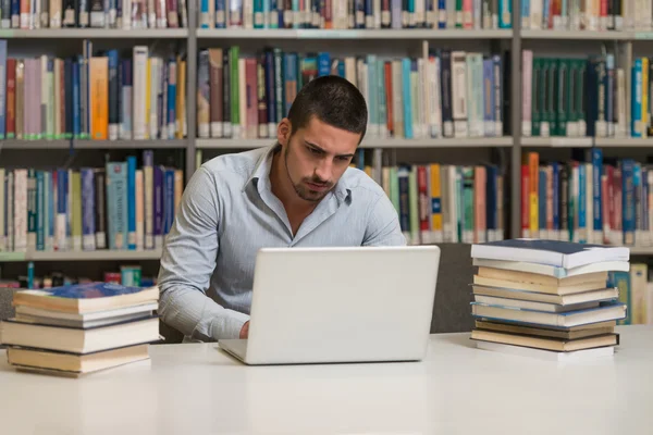 Ung Student med sin Laptop i ett bibliotek — Stockfoto