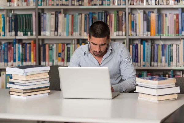 Ung Student med sin Laptop i ett bibliotek — Stockfoto