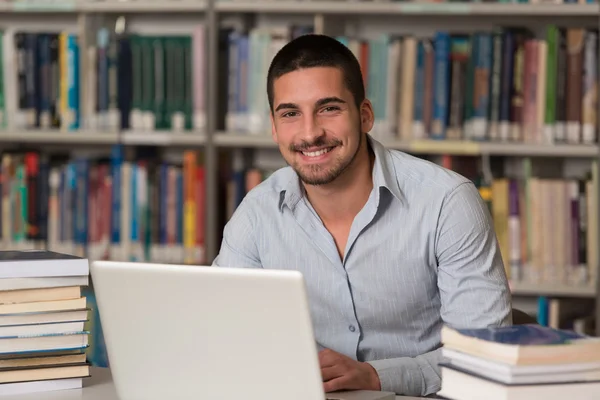 Ung Student med sin Laptop i ett bibliotek — Stockfoto