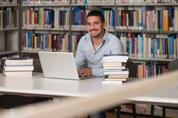 Mladý Student pomocí jeho notebook v knihovně — Stock fotografie