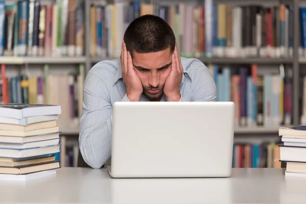 Estudiante estresado haciendo su tarea en el escritorio — Foto de Stock