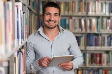 bir kitaplıkta bir tablet bilgisayar kullanarak öğrenci