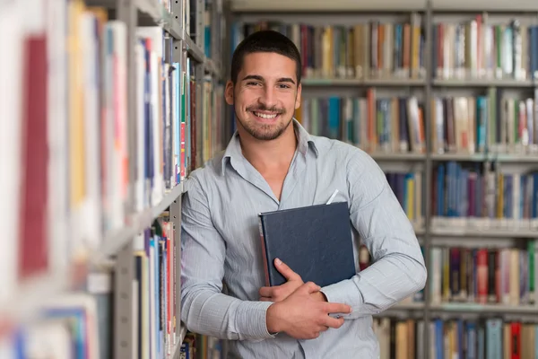 Studente universitario maschio in una biblioteca — Foto Stock