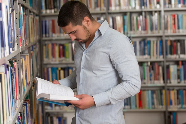 Feliz estudiante masculino con libro en la biblioteca —  Fotos de Stock