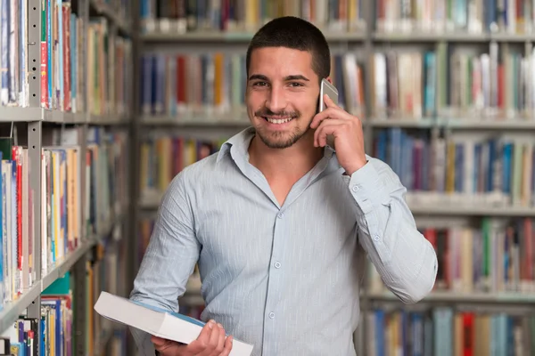 Studentowi rozmawia przez telefon w bibliotece — Zdjęcie stockowe