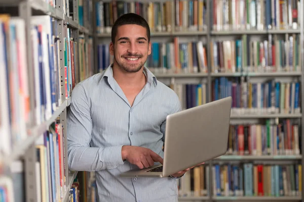 Felice studente maschio con computer portatile in biblioteca — Foto Stock