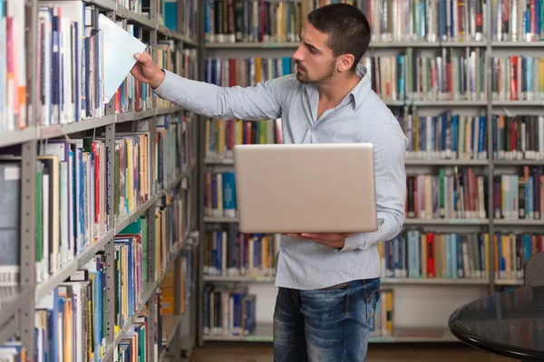 Heureux étudiant masculin travaillant avec ordinateur portable dans la bibliothèque — Photo