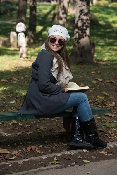 Frau sitzt im Park und liest Buch — Stockfoto