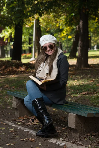 Attraktiv kvinna läser bok i höst skog — Stockfoto