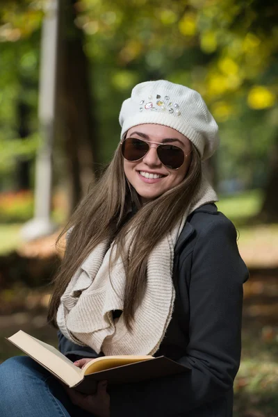 Donna seduta in un parco e libro di lettura — Foto Stock