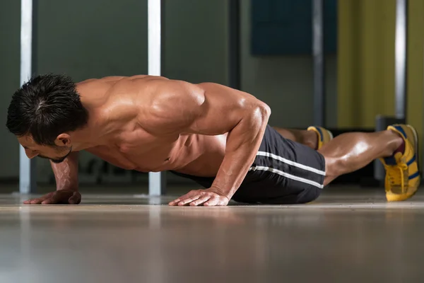 Junger Mann macht Liegestütze im Fitnessstudio — Stockfoto