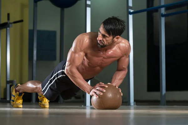 Aantrekkelijke mannelijke atleet push-ups uitvoeren op medicijnbal — Stockfoto