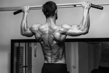 Genç adam spor salonunda sırt egzersizleri yapıyor