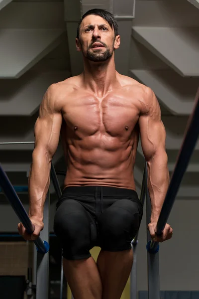 Ajuste atleta haciendo ejercicio en barras paralelas — Foto de Stock