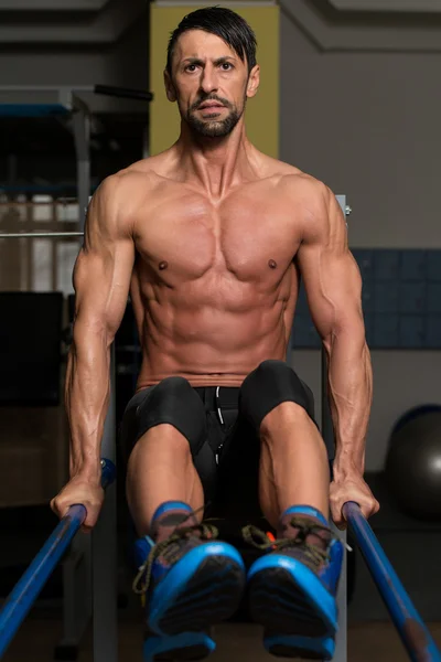 Atleta fazendo exercício de peso pesado em barras paralelas — Fotografia de Stock