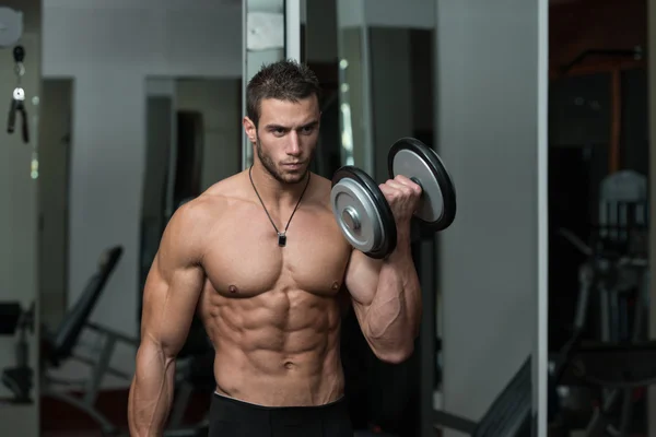 Jovem masculino fazendo exercícios de bíceps no ginásio — Fotografia de Stock