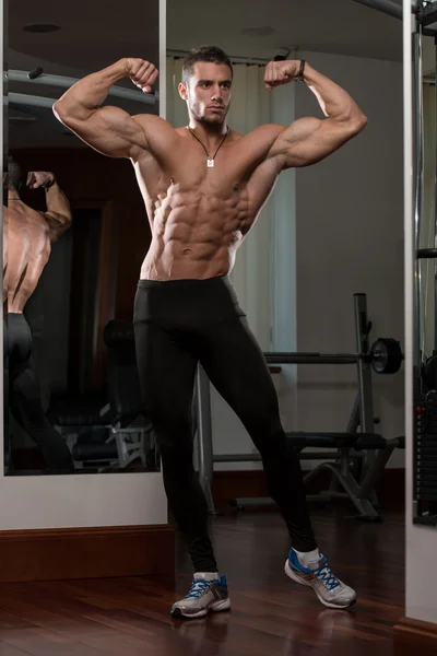Mladý muž provádějící přední dvojitý Biceps pozice — Stock fotografie