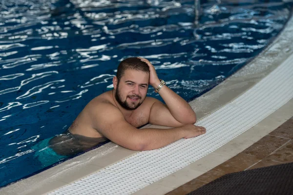 Υπέρβαρα άνθρωπος αναπαύεται χαλαρό στην άκρη της πισίνας — Φωτογραφία Αρχείου