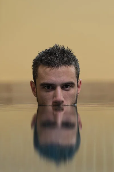 Hombre nadando en piscina con cara medio sumergida — Foto de Stock