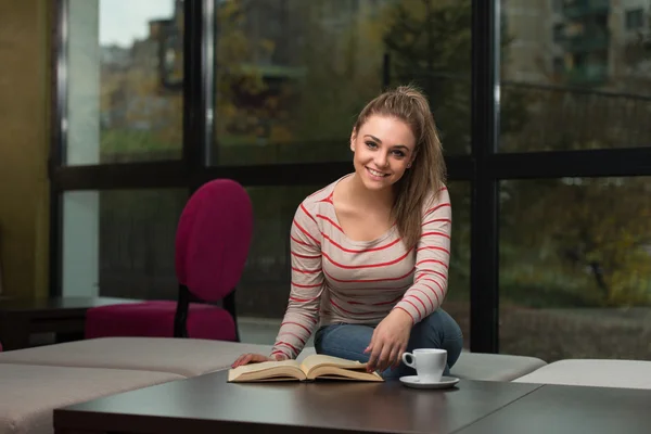 Smiling Young Student In Cafe Reading Book