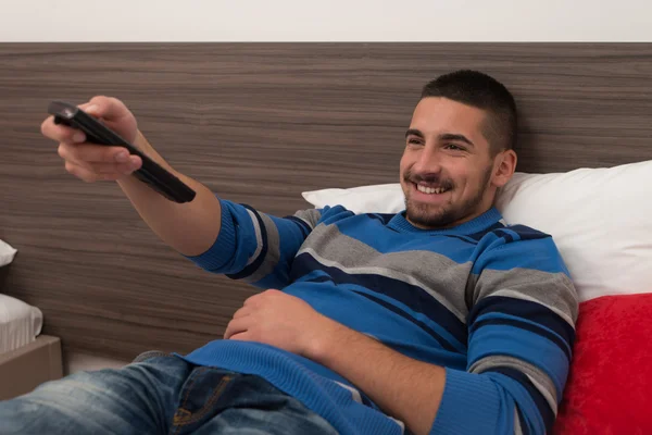 Male Student On Bed With Remote Control — Stock Photo, Image