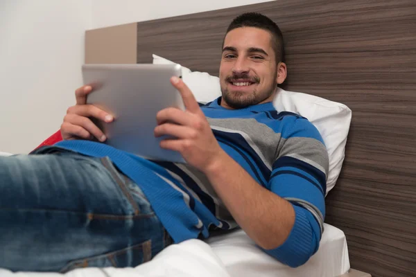 Glücklicher Mann im Schlafzimmer mit Tablet — Stockfoto