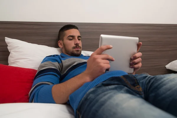 Junger Mann mit Tablet im Bett — Stockfoto